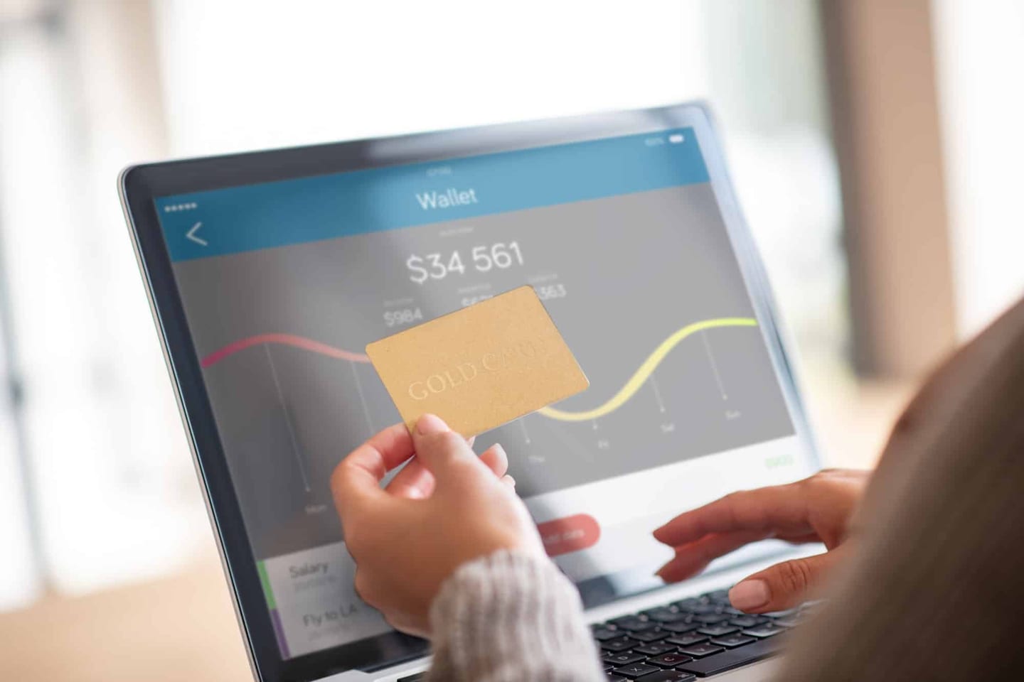 Woman holding a bank card in front of an online banking screen