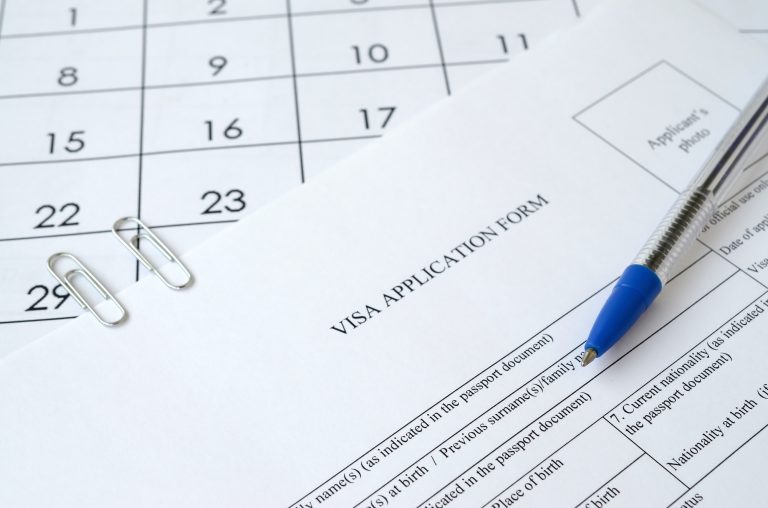 Typical Visa application form and blue pen on paper calendar page close up
