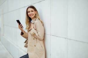 A happy trendy woman is using her phone outdoors for telecommunications.