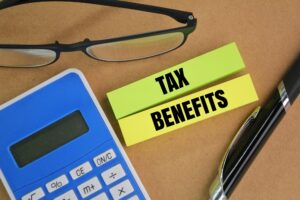 calculator, pen, glasses and colored paper with the word TAX BENEFITS