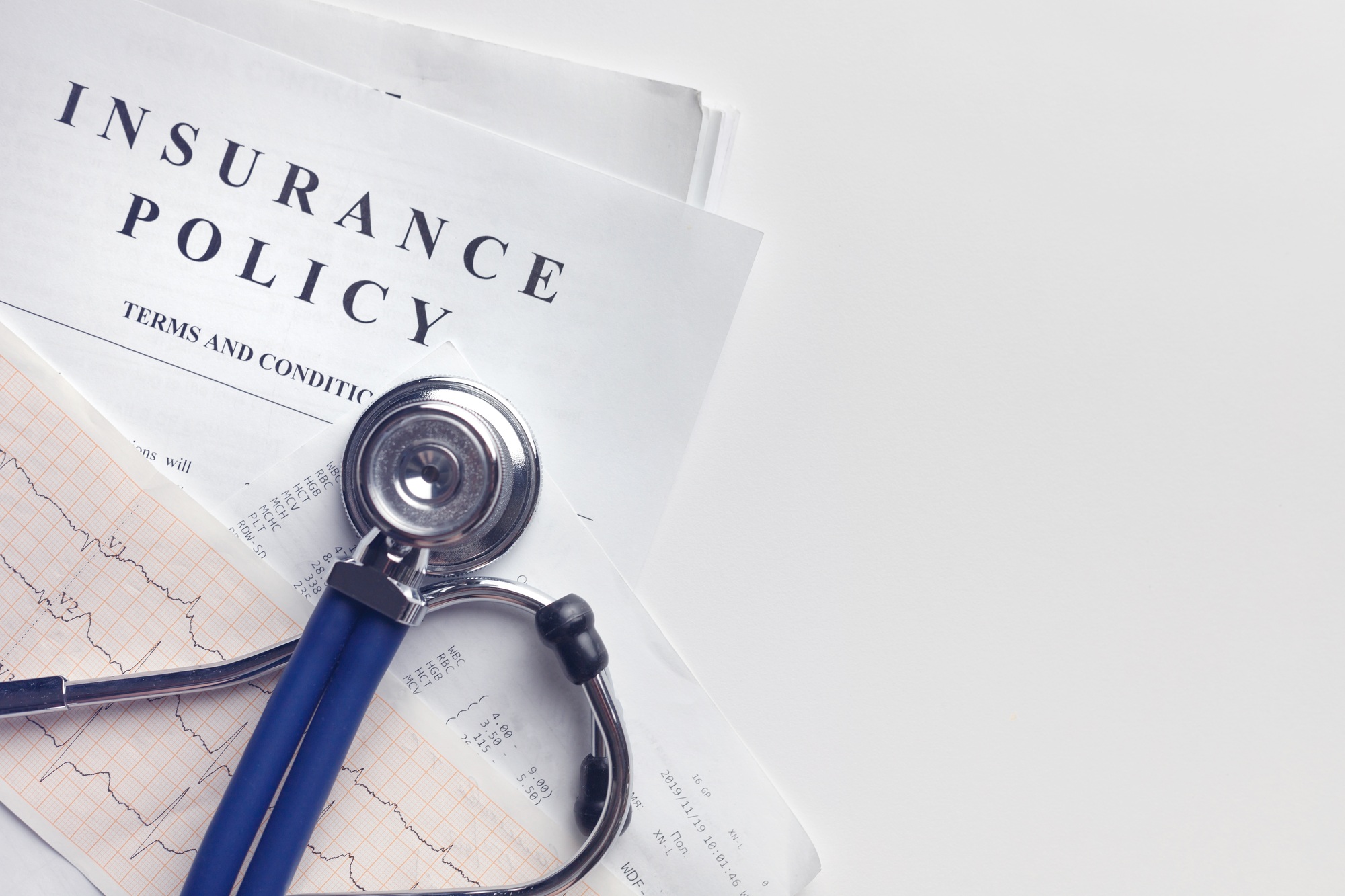 Health insurance form, medical stethoscope and cardiogram chart with copy space on white