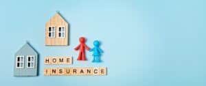 Home insurance message and wooden houses over blue background