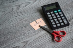 Scissor, calculator and note with text COST.
