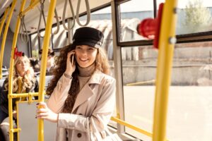 selective focus of smiling woman talking on smartphone while riding in public transport