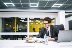Young office manager working with papers and computer working at office. Man in a suit working.